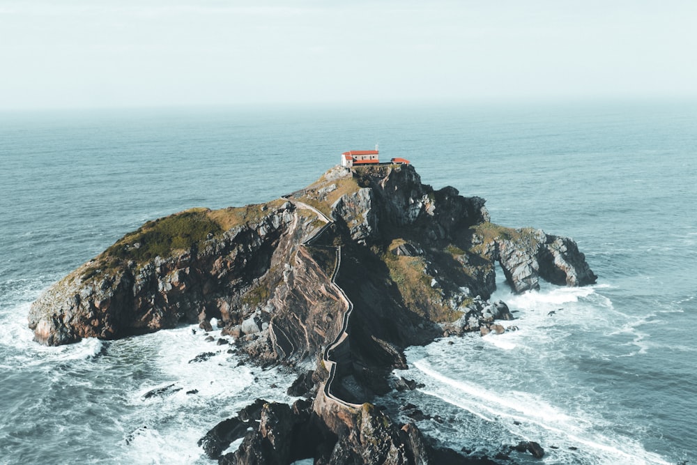 una piccola casa in cima a una piccola isola in mezzo all'oceano