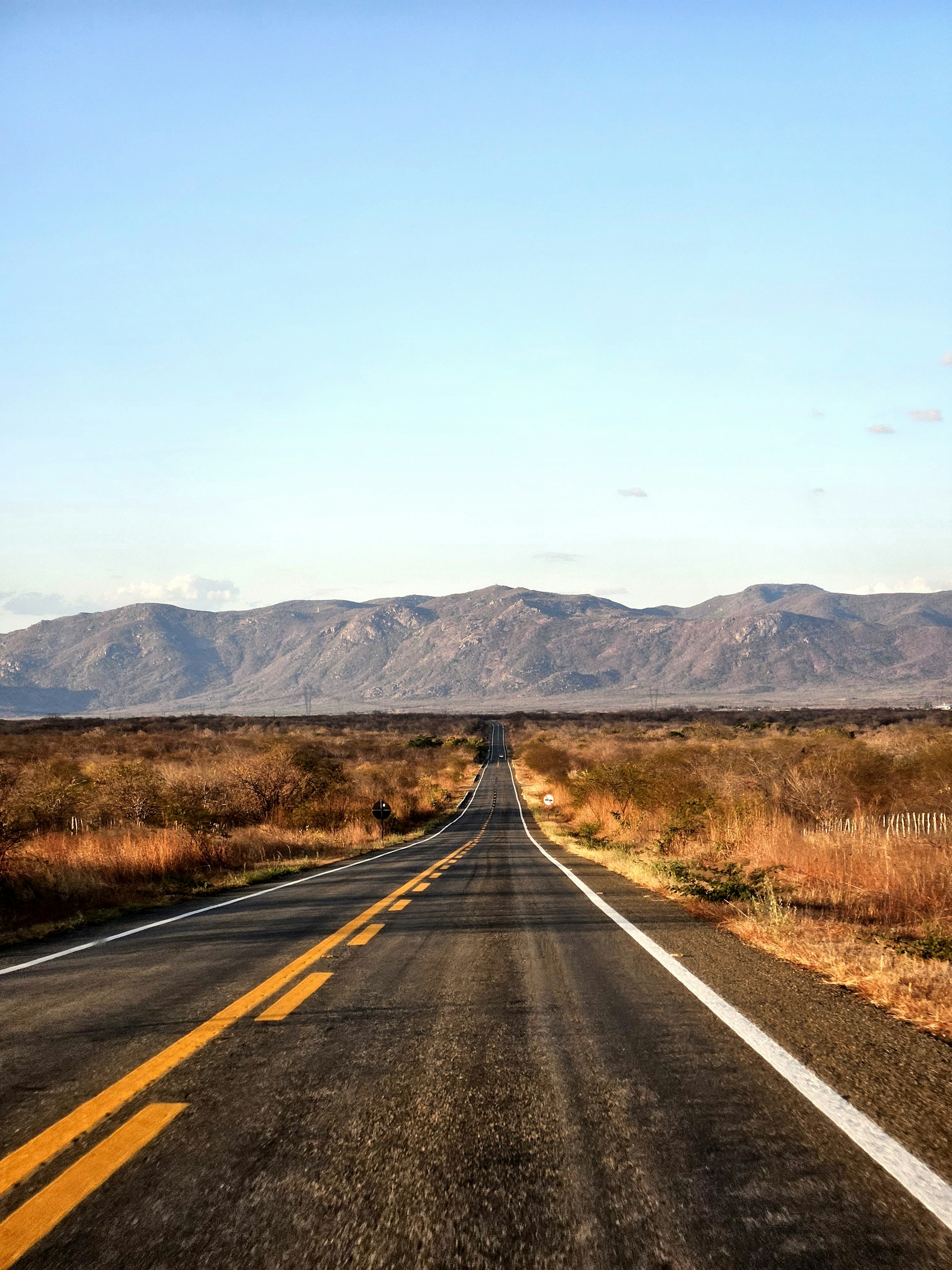 an empty road with mountains in the background