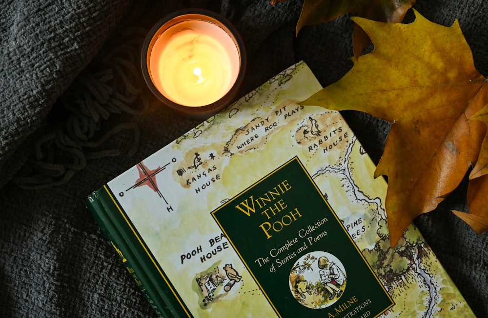 a book sitting on top of a blanket next to a candle