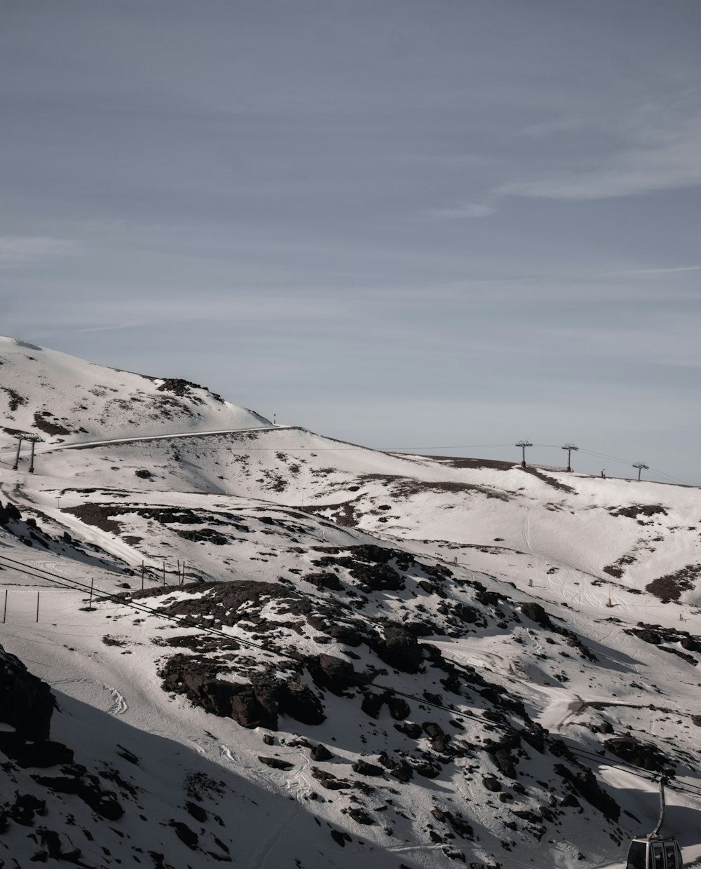 ein schneebedeckter Berg mit einem Skilift in der Ferne