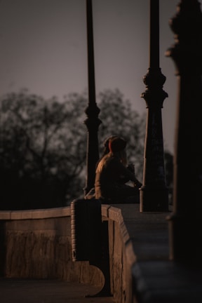 A quiet moment of reflection: a person sitting alone on worn steps, bathed in the glow of a single warm streetlamp.