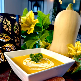 A steaming bowl of creamy butternut squash soup garnished with toasted pumpkin seeds.