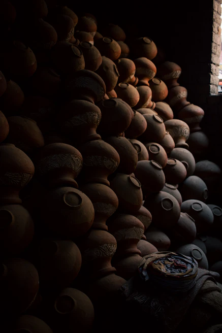 A cozy studio corner filled with clay pots in various bright colors drying under soft natural light