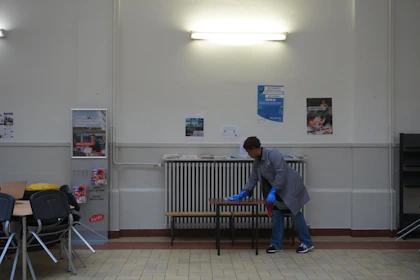 A Hygienia Immaculate professional wiping down conference room tables, readying the space for a business meeting.