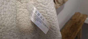 Center-fold woven wash labels neatly arranged, highlighting fine thread work and clear care instructions