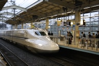 Passengers boarding a modern train at a bustling Indian railway station.