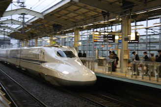 Modern Tokyo train station platform with sleek trains and travelers in motion.