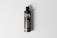 A tall, black cylindrical bottle with a sleek design is placed upright on a light gray background. The bottle features the word 'OIL' prominently displayed in large, white letters at the top, followed by the smaller text 'BOTTLE MOCKUP'. There are multiple lines of text below, which appear to provide additional details, likely about the product or its usage.