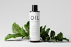 a bottle of oil sitting next to a plant