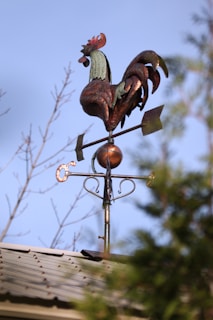 A row of colorful rooster weathervanes lined up on a workshop table, ready for shipment.