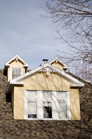 a yellow house with a clock on the top of it