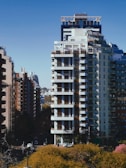 a tall white building sitting next to a lush green park