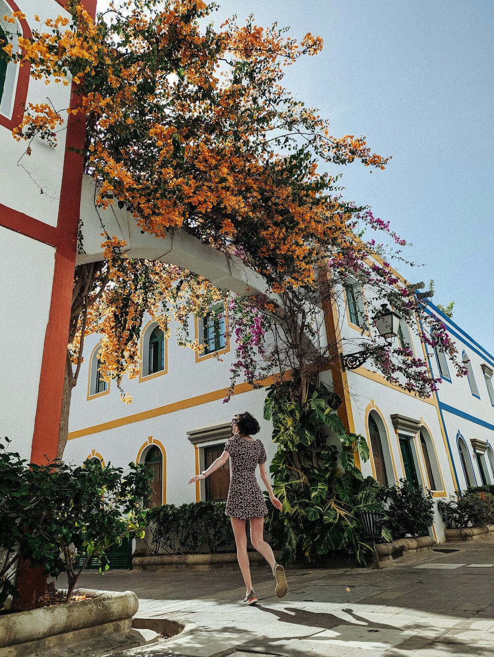 a woman walking down a street past a tall white building