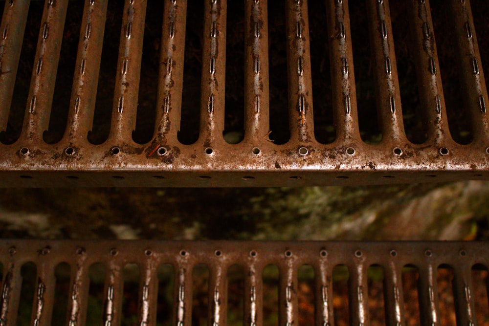 a close up of a metal grate with a tree in the background