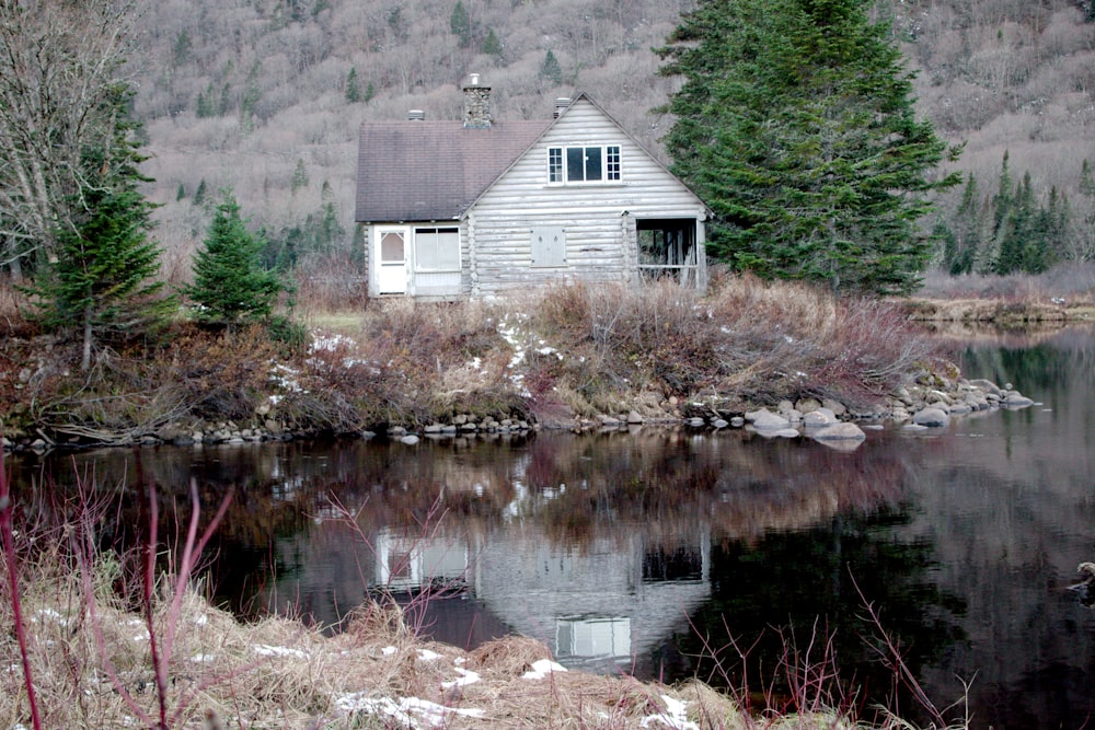 a small white house sitting next to a body of water