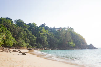 A luxurious tropical villa overlooking a serene beach, bathed in soft golden sunlight.