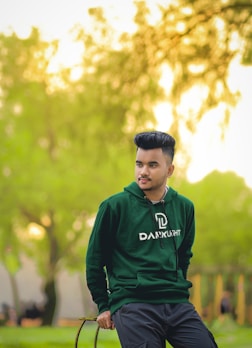 Model wearing a vibrant, modern hoodie walking through a city park at sunset