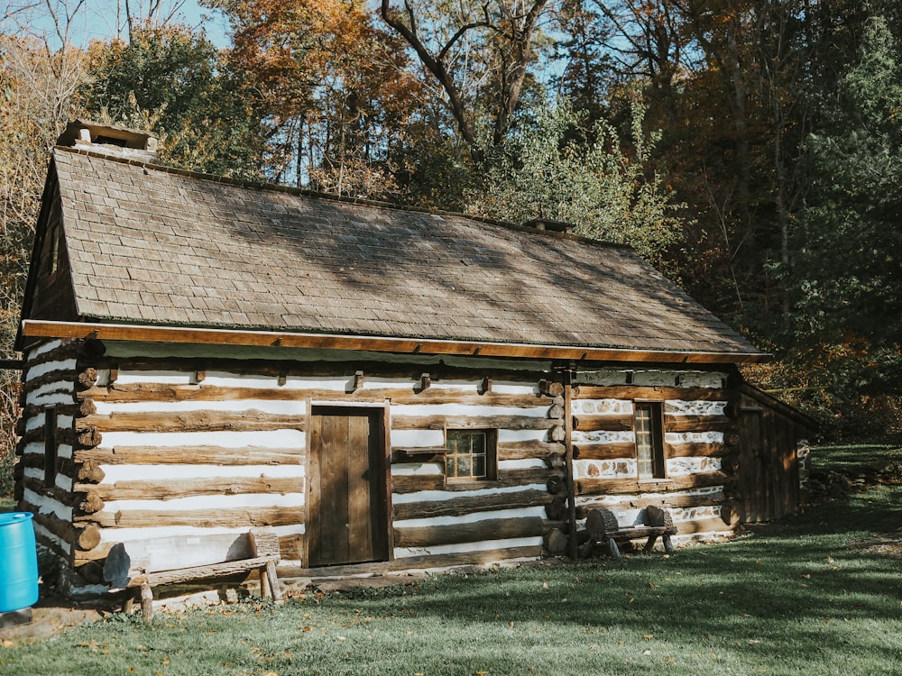 a log cabin in the woods with a blue barrel next to it