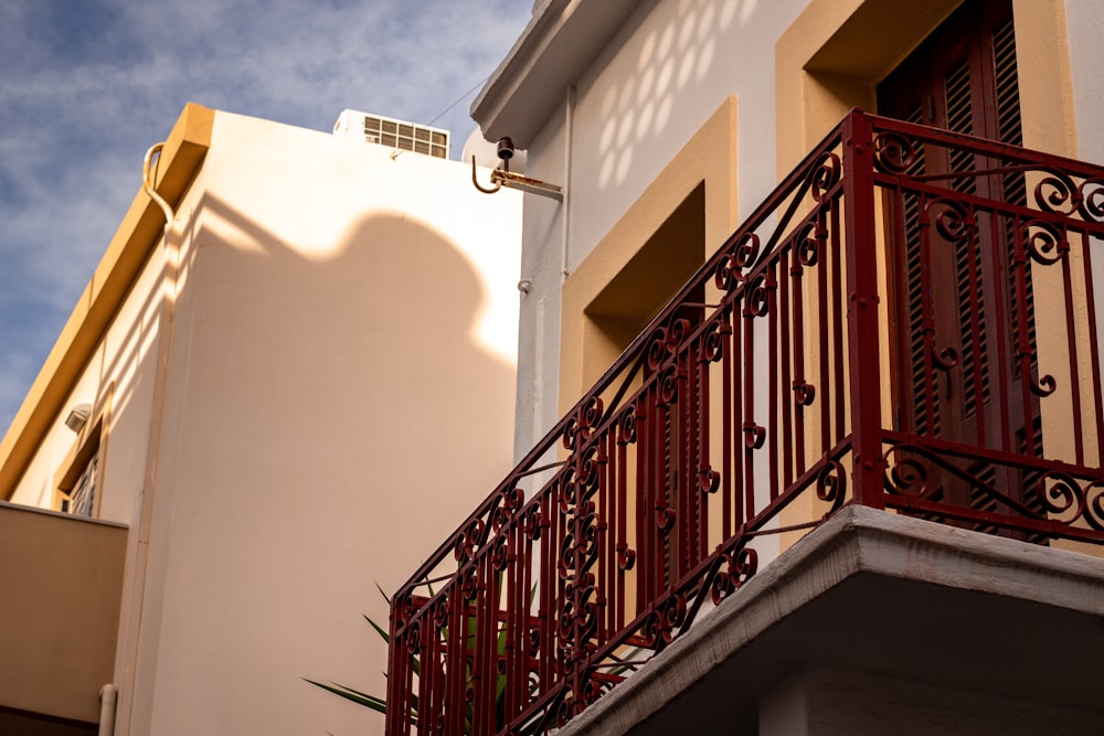 a balcony with a red iron railing and a white building