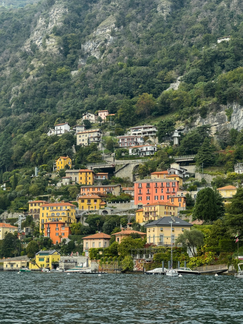 a small village on the side of a mountain next to a body of water