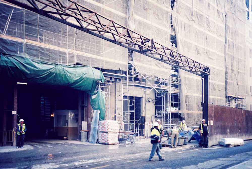 a group of people standing outside of a building under construction