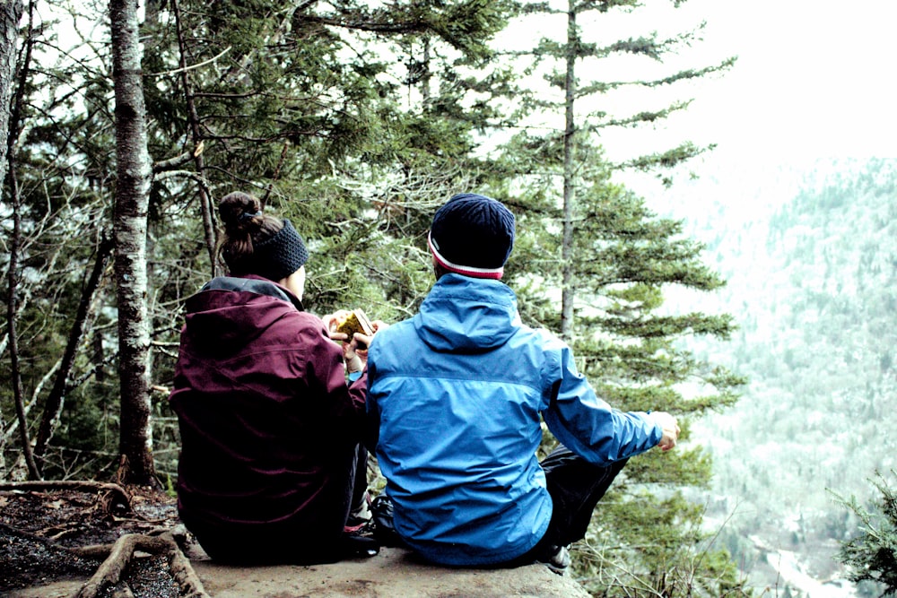 zwei Menschen sitzen auf einem Felsen im Wald
