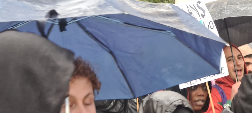 a group of people standing around each other holding umbrellas