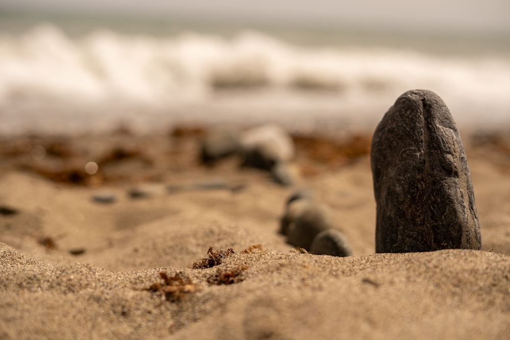 a rock sticking out of the sand on a beach