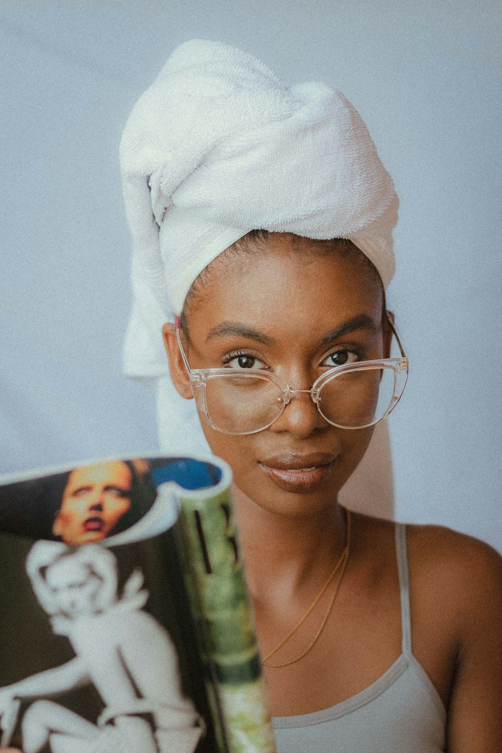 a woman with a towel on her head holding a magazine