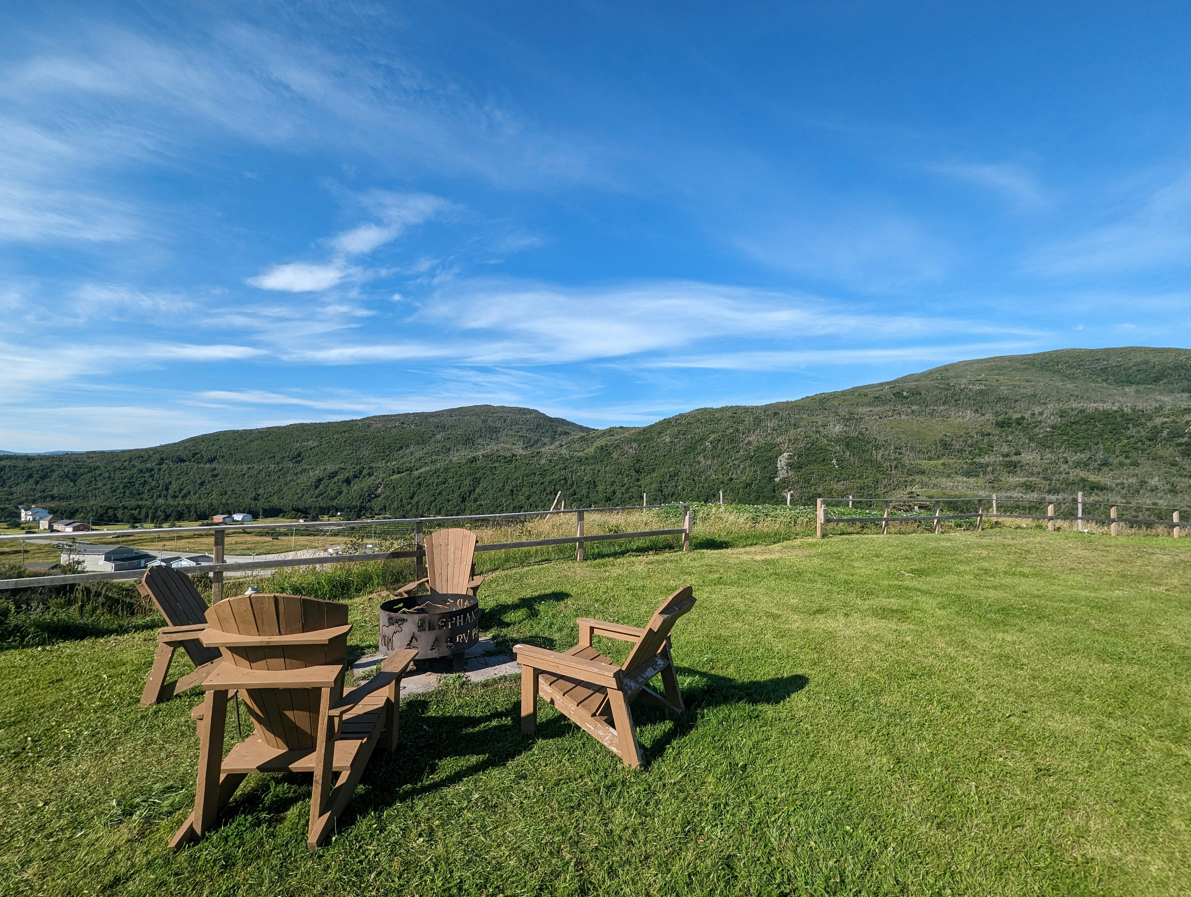 two chairs and a fire pit in a grassy field, Camping at Elephants Head RV Park in Gros Morne National Park, looking towards Elephant