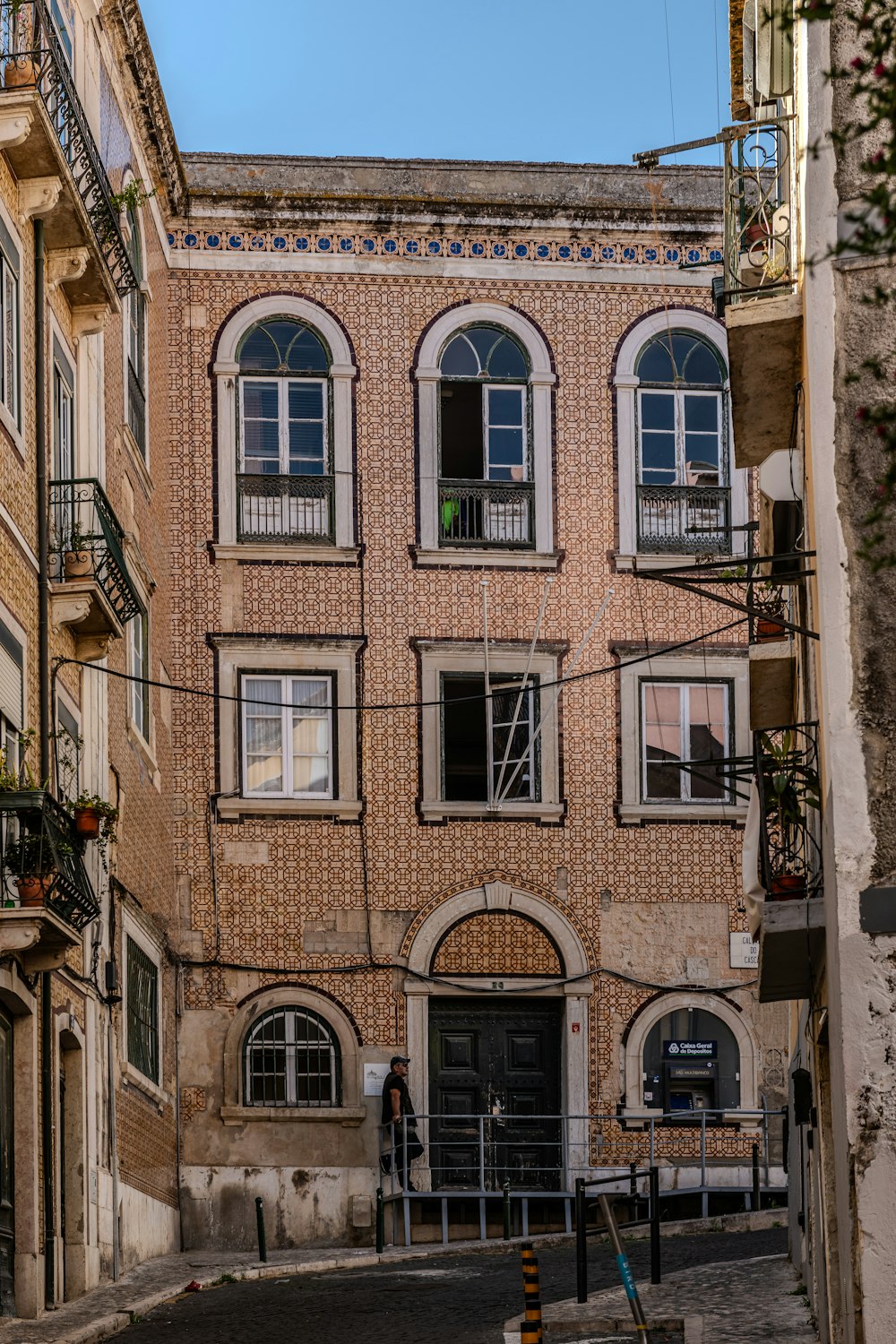 a brick building with arched windows on a narrow street