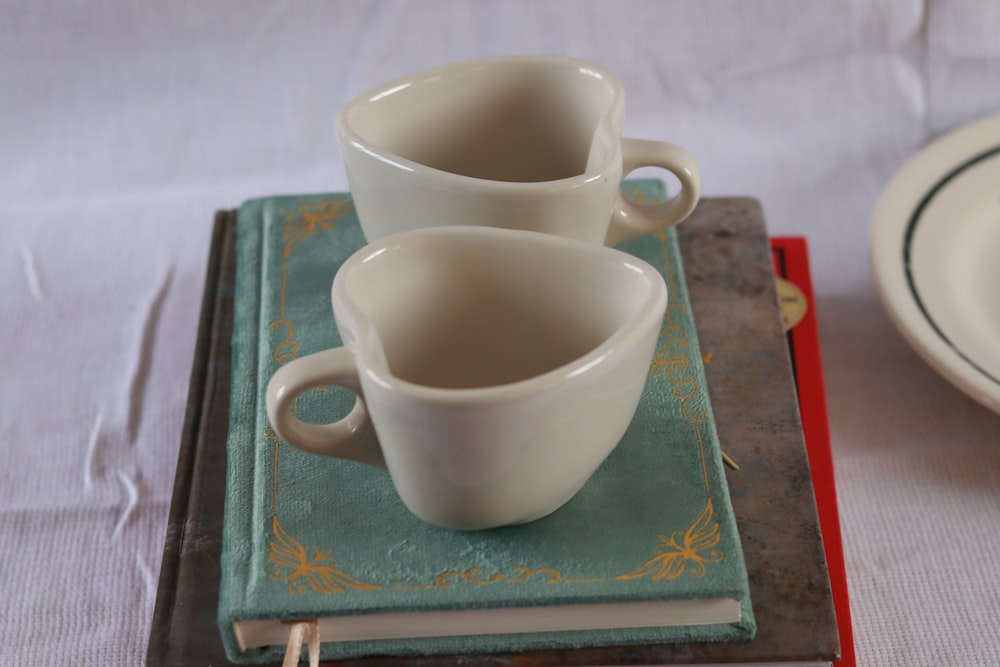 a couple of cups sitting on top of a book