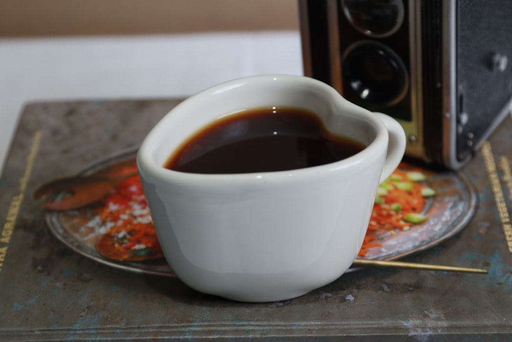 a cup of coffee sitting on a plate next to a camera