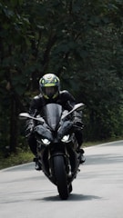 A close-up of a motorcyclist wearing a sleek helmet and protective jacket, gripping the handlebars on an open road.