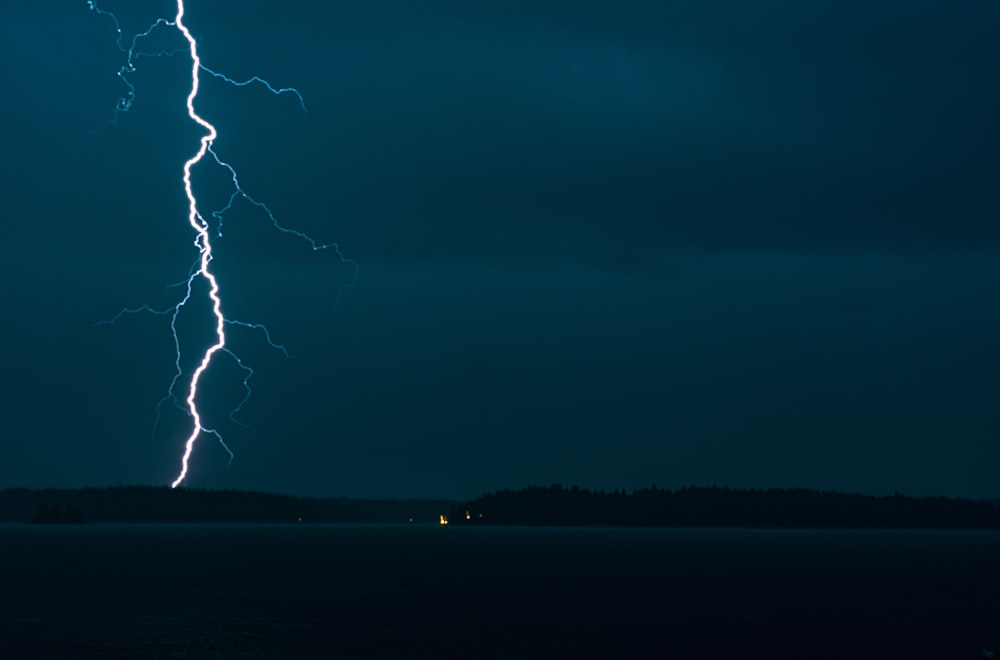 a lightning bolt strikes across the sky over a body of water