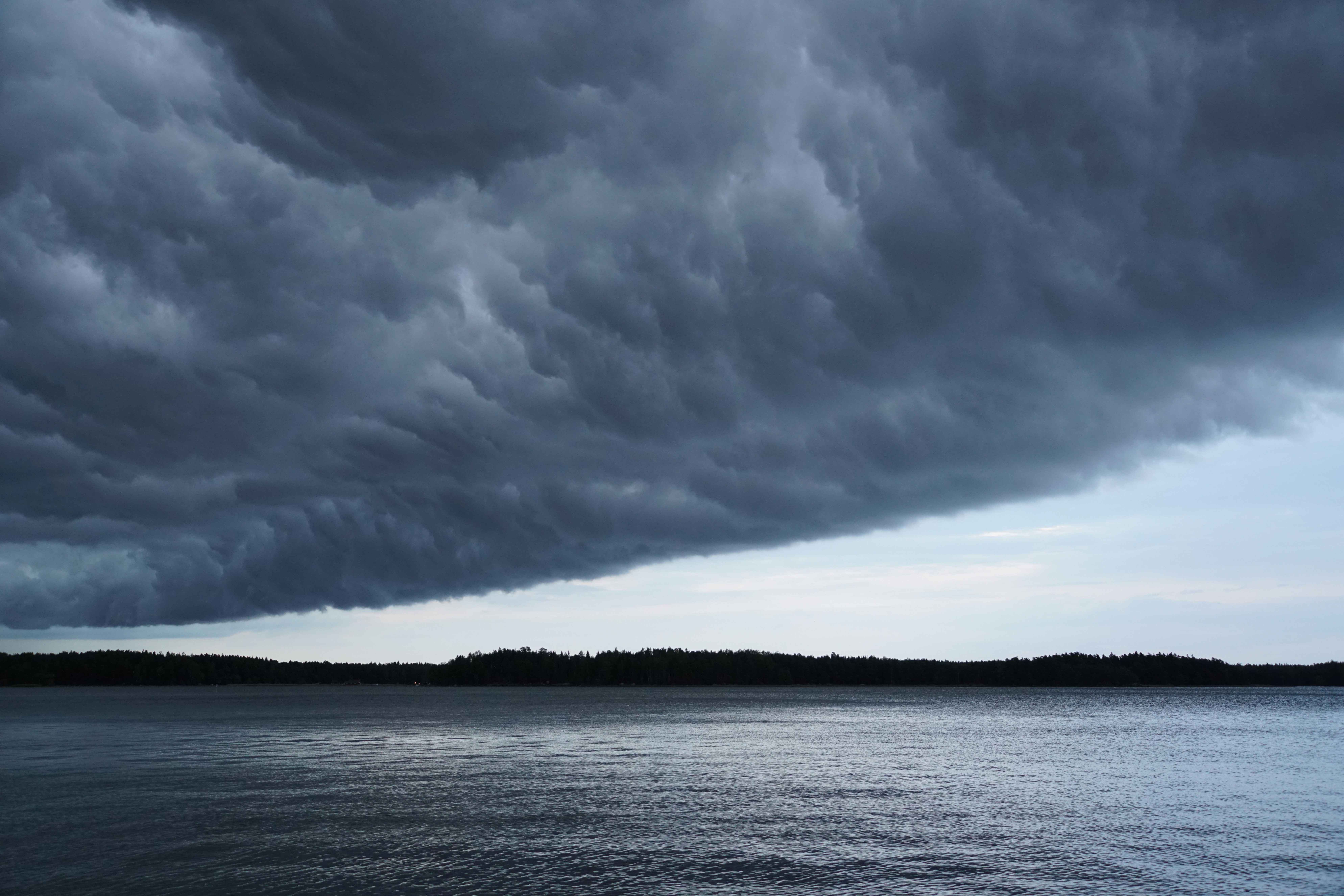 a large dark cloud hangs over a body of water