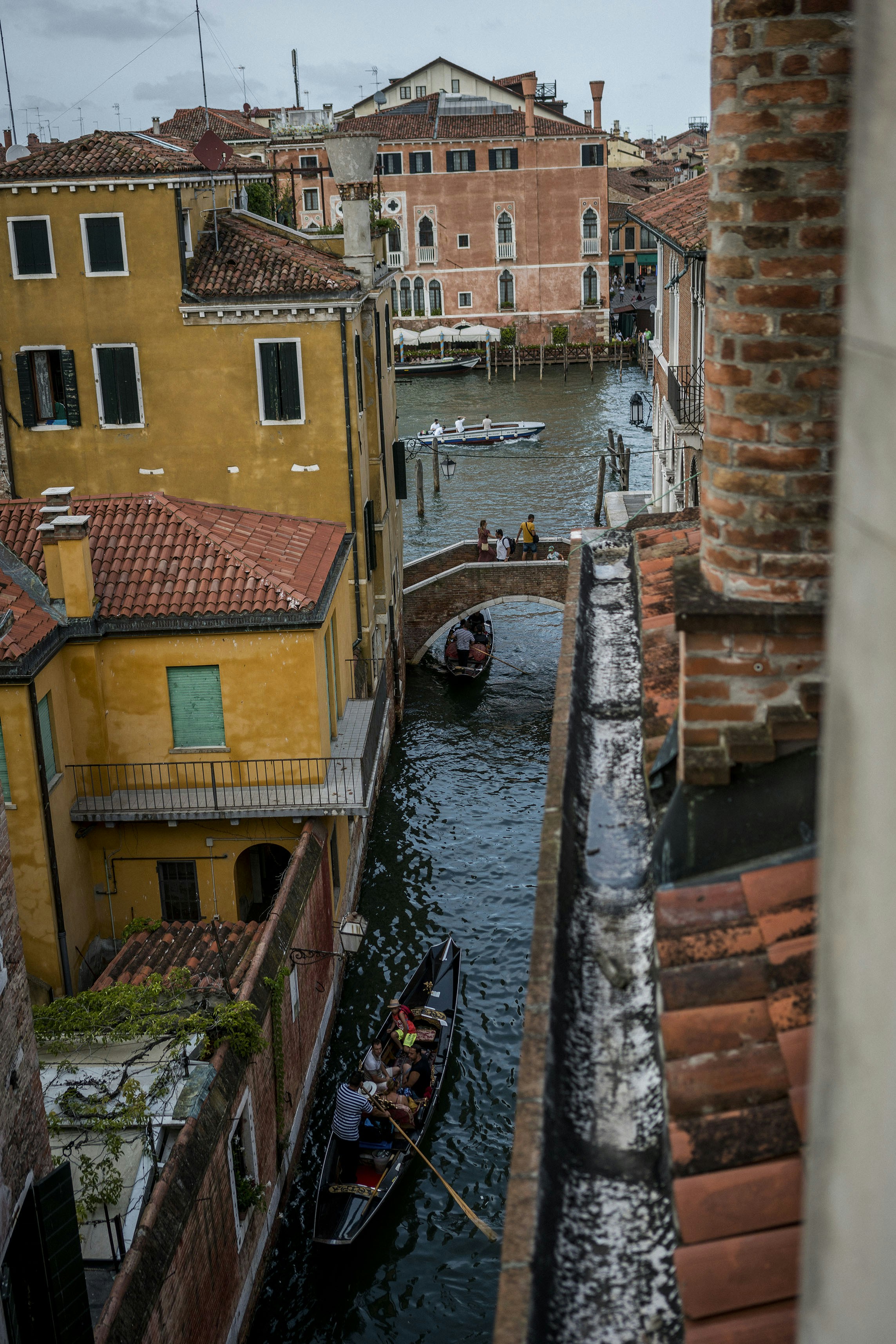 a narrow canal with gondolas and buildings in the background