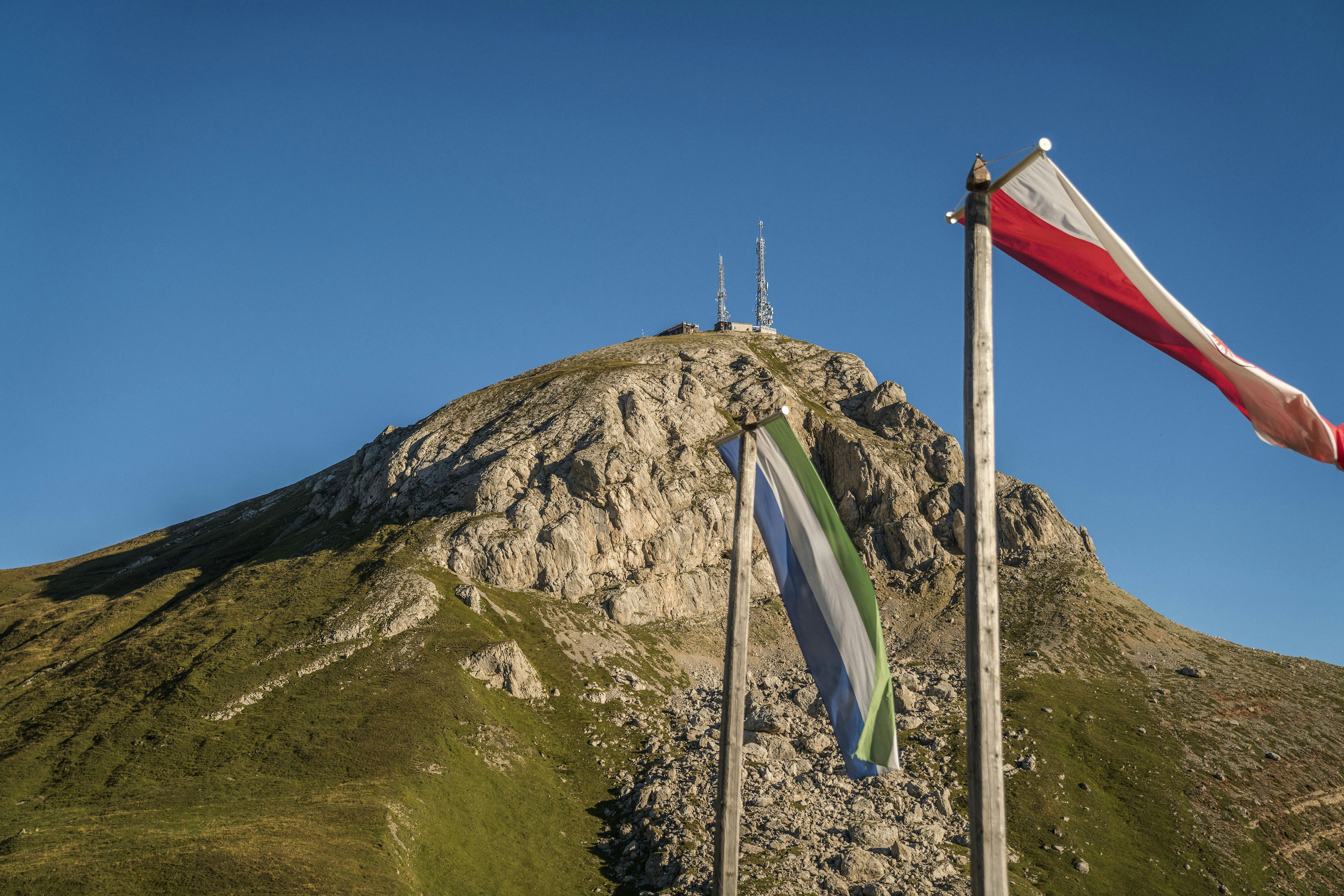 two flags are flying in front of a mountain