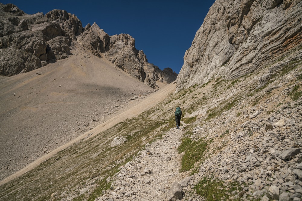 a person hiking up a rocky mountain trail