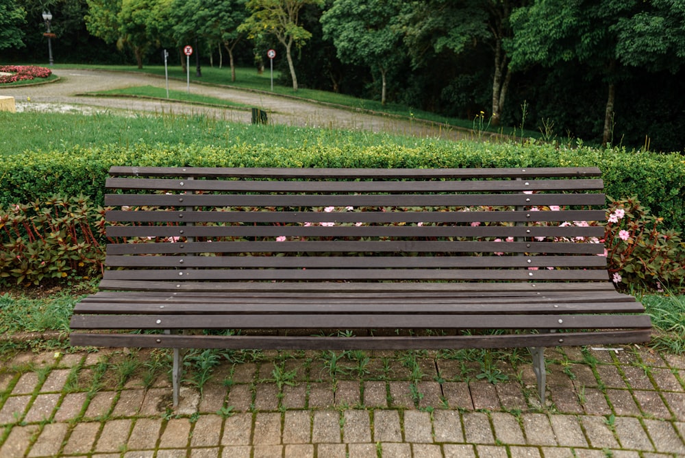 um banco de madeira sentado em frente a um parque verde exuberante