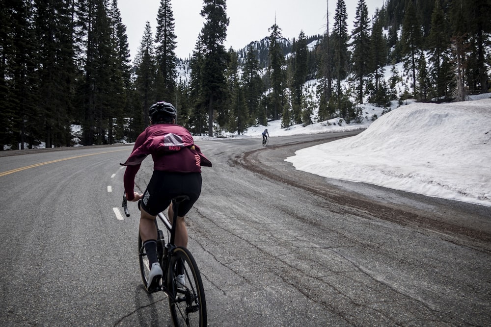 a man riding a bike down a snow covered road
