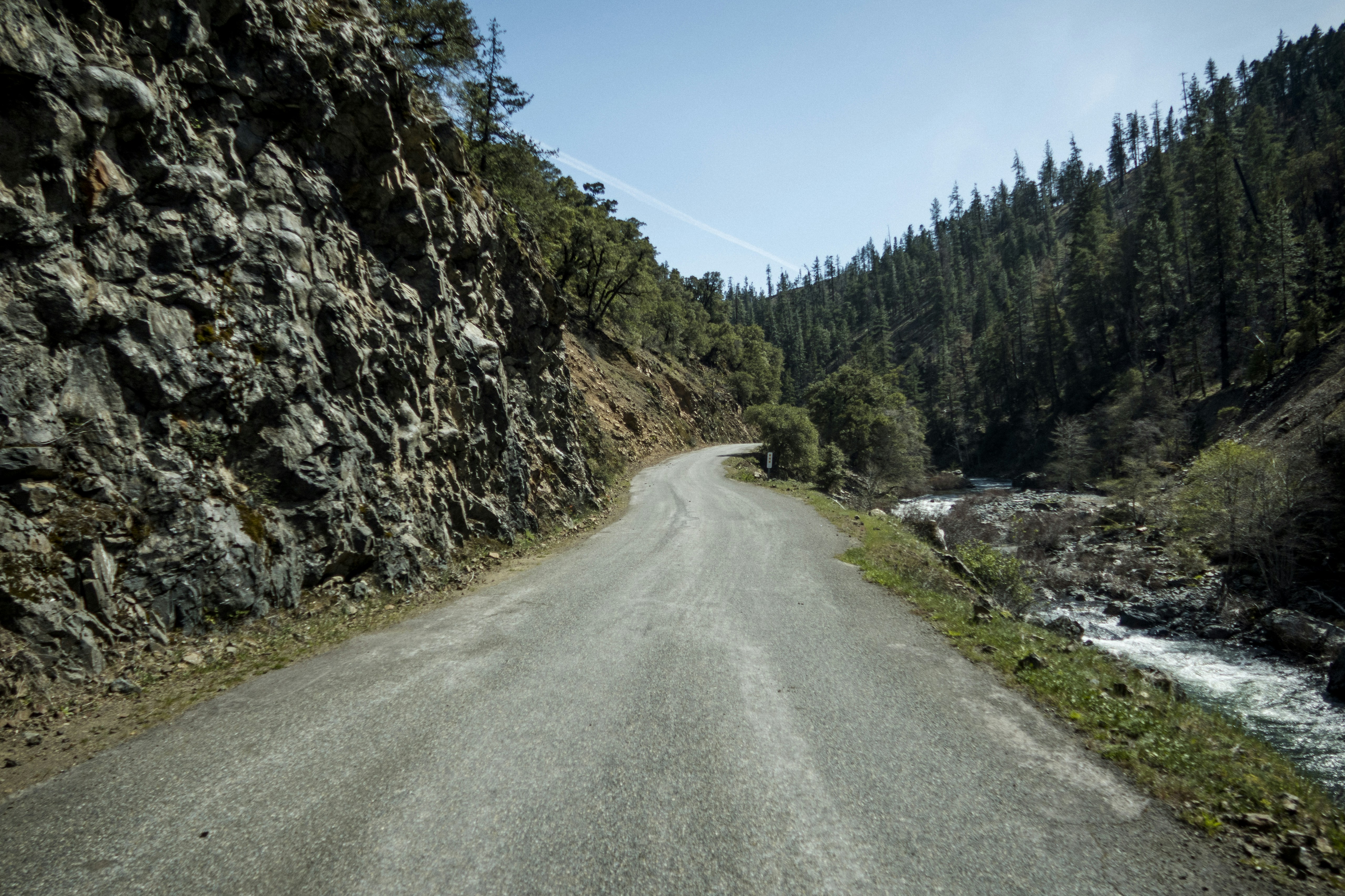 a car driving down a mountain road next to a river
