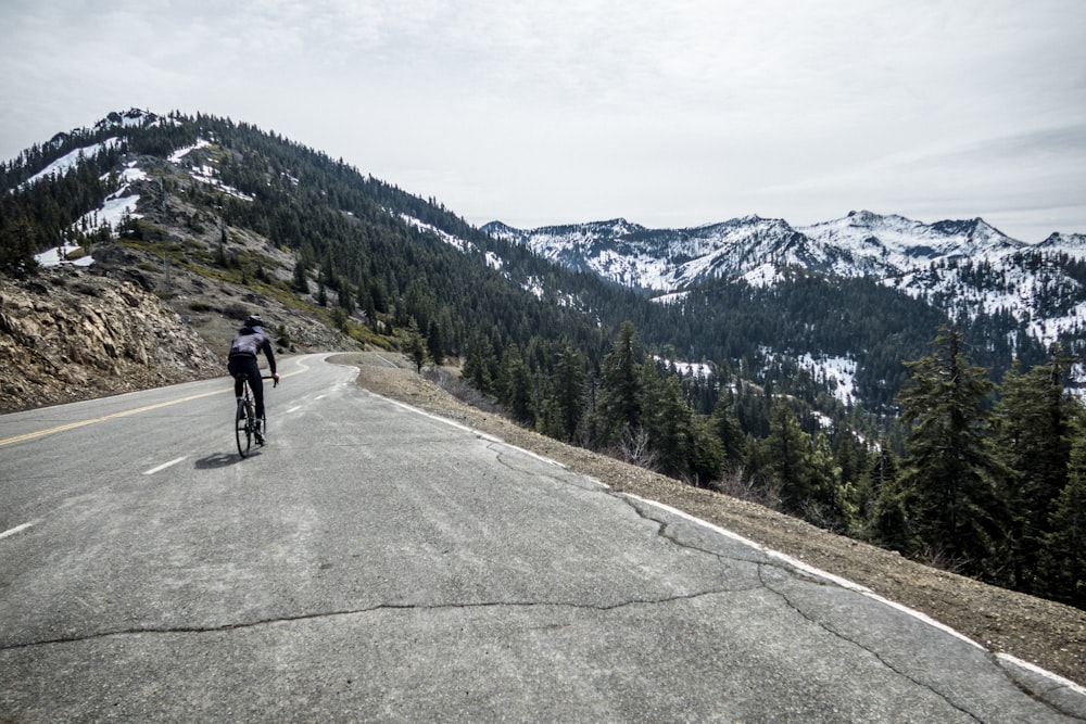 a bicyclist rides down a mountain road
