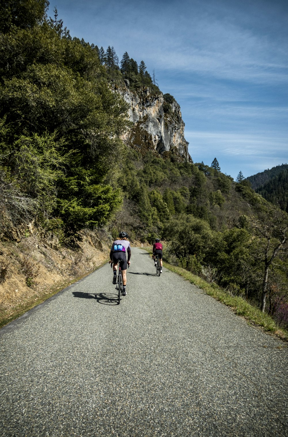 a couple of people riding bikes down a road