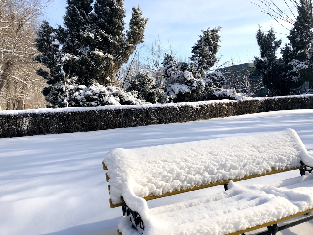 a bench covered in snow in a park