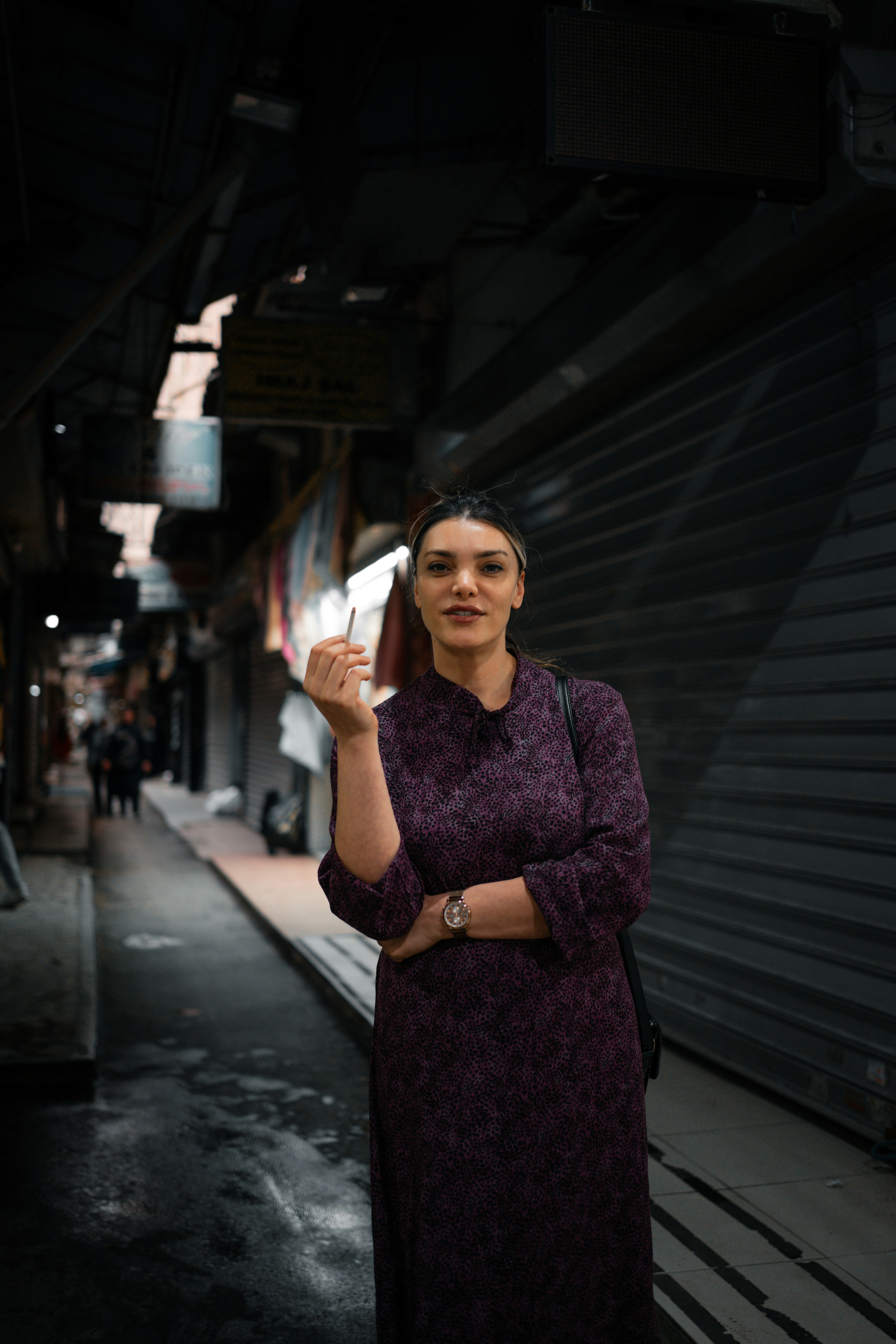 a woman in a purple dress standing in a dark alley