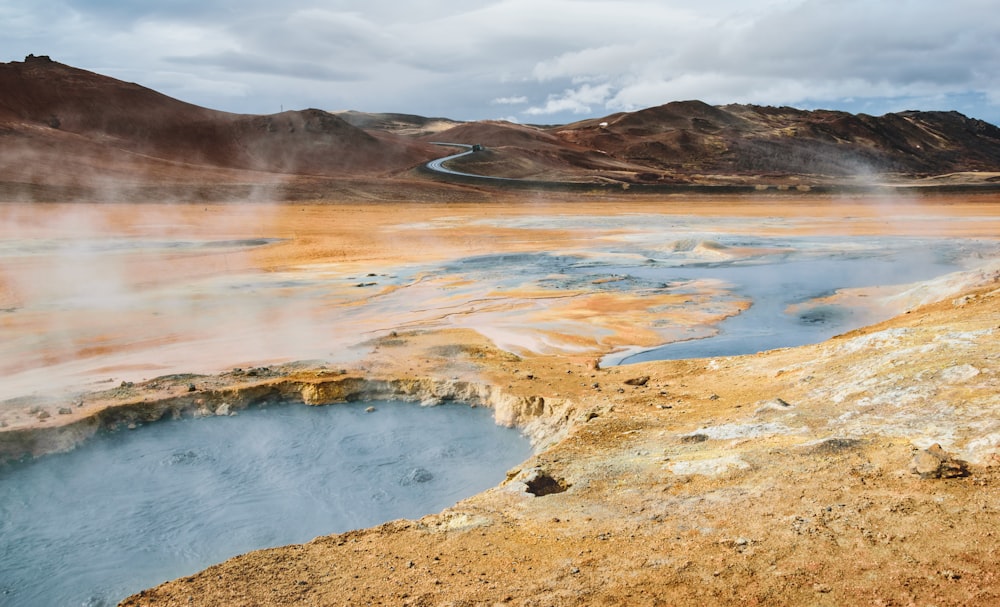 a body of water surrounded by mountains under a cloudy sky