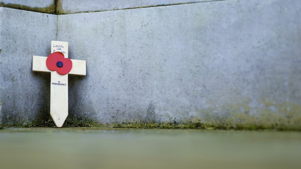 a white cross with a red flower on it