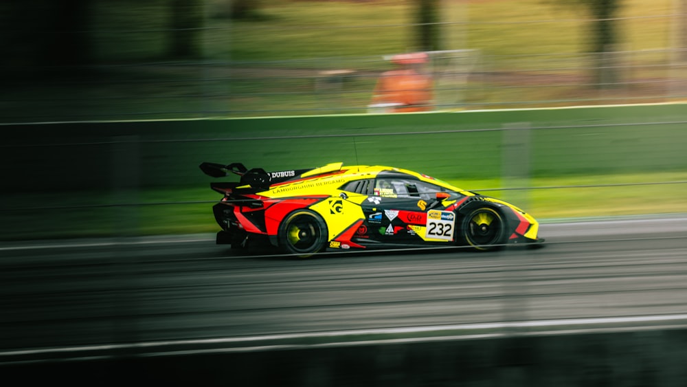 a yellow and red car driving down a race track