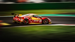 a red and yellow race car driving on a track